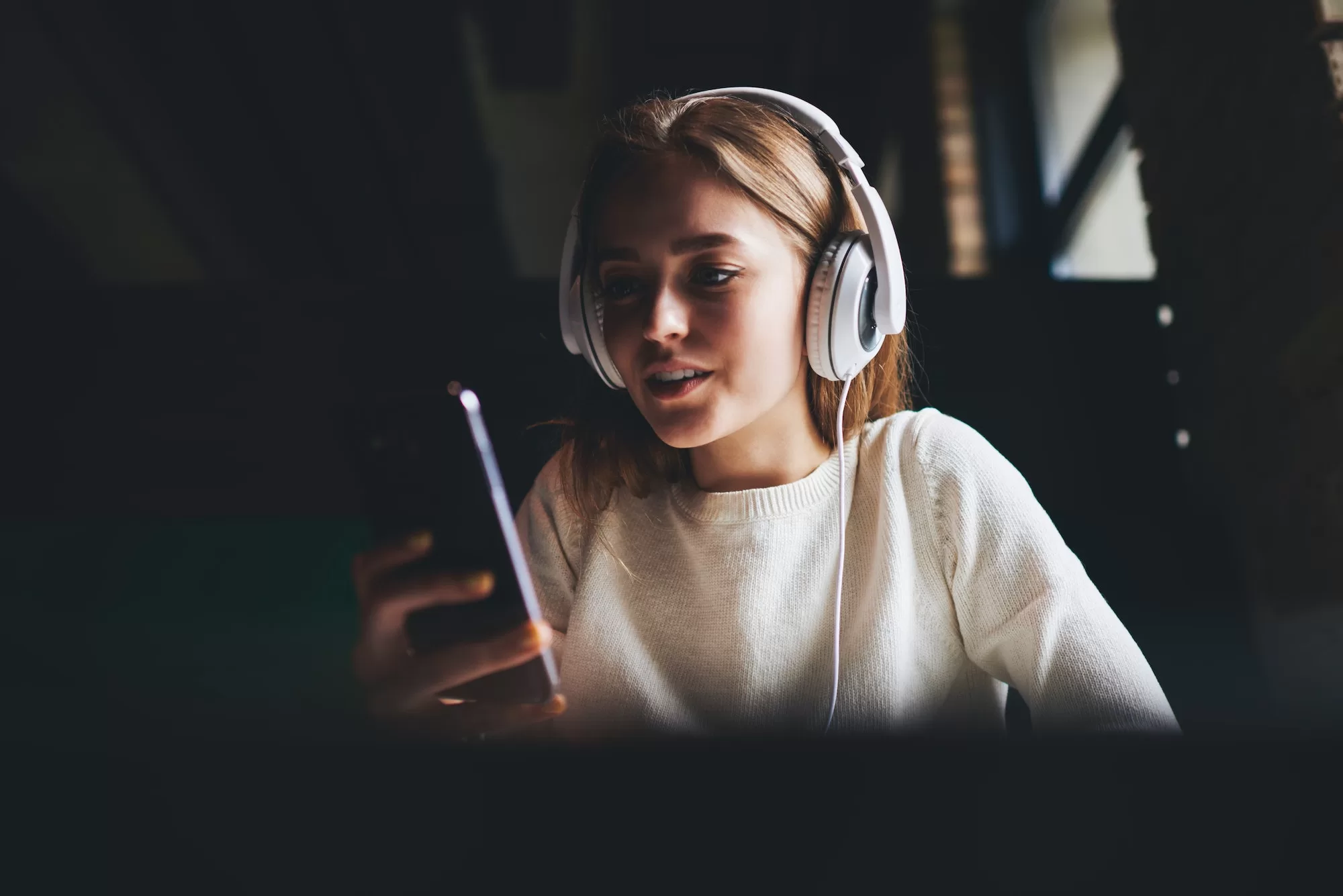 Positive woman listening to music and using phone